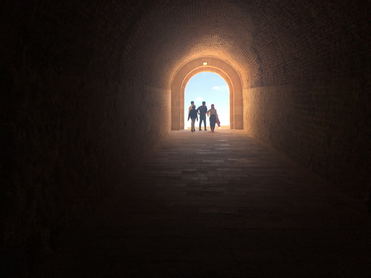 A group of silhouetted people step out of a tunnel